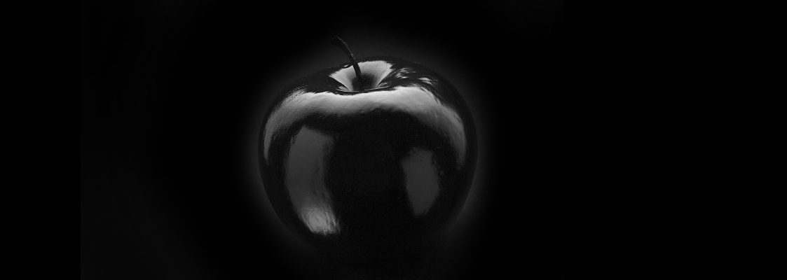 Ein schwarz glänzender Apfel auf schwarzem Hintergrund