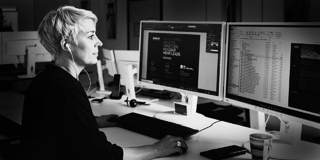 Webseitenredesign bei arven.io Eine arvenio Mitarbeiterin vor zwei Bildschirmen mit Ohrstöpseln im Ohr
